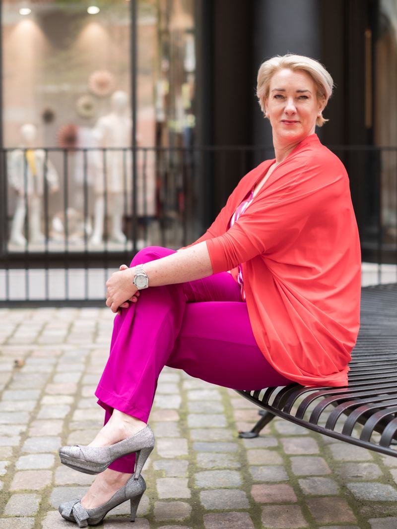 Sandra Putzer sitzt auf einer Bank vor einem Schaufenster